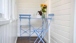 A blue metal folding table with a glass vase containing yellow flowers on a white wall. - Bright 1BR Retreat | Near Downtown & Airport (Pittsburgh)
