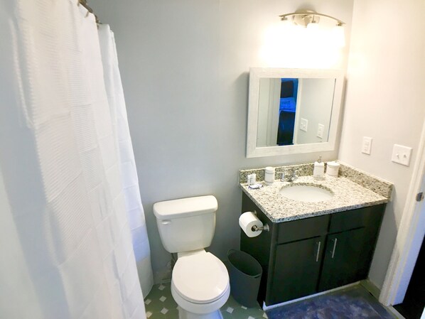 Une salle de bain équipée de toilettes, d’un lavabo, d’un miroir et d’une poubelle.