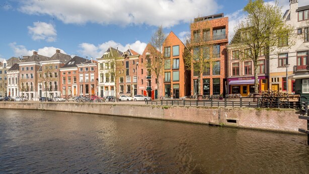 A canal with buildings along the water's edge, featuring a mix of traditional and modern architecture.