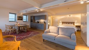 A spacious living area with a sofa, a dining table with chairs, and a kitchen in the background.