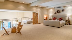 A spacious bedroom with a large bed, a sofa, a wooden chair, and a small table. There is a balcony with a railing and a view of the outside. - Uber Luxurious NYC-Style Penthouse, Two Minutes Walk from Long Street (Cape Town)