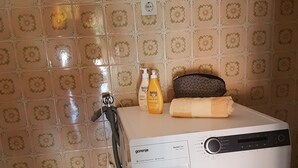 Una lavadora en una habitación con baldosas estampadas y una toalla colgada en la pared.