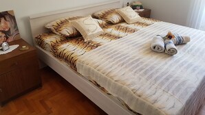 Una cama bien hecha con almohadas estampadas, una colcha blanca y toallas enrolladas al lado.