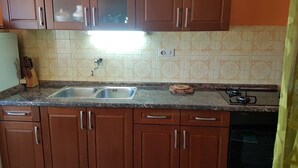 Una cocina con gabinetes marrones, un lavamanos doble y una estufa.
