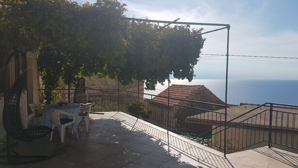 Un patio al aire libre con una mesa y sillas, una planta colgante y vistas al mar.