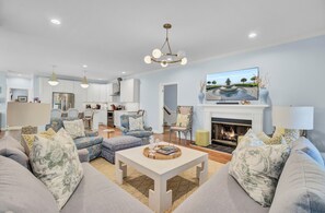 A spacious living room with a fireplace, comfortable seating, and a television displaying a scenic view.