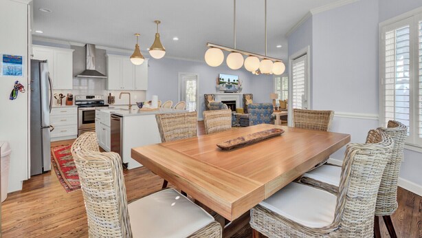 A spacious kitchen with a central island, white cabinetry, and modern pendant lighting.
