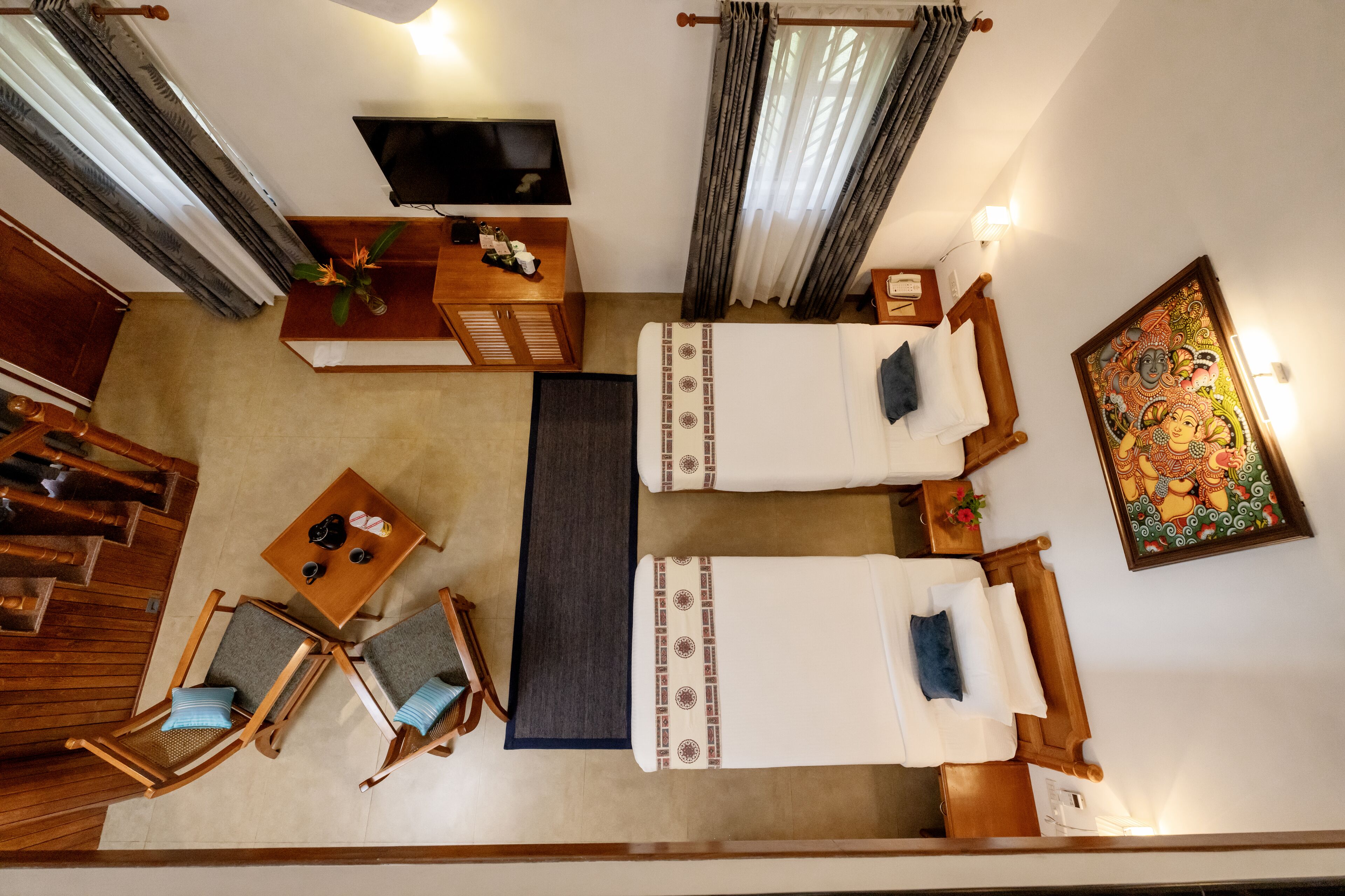 Quarto com duas camas, televisão, escrivaninha, cadeiras e um quadro.