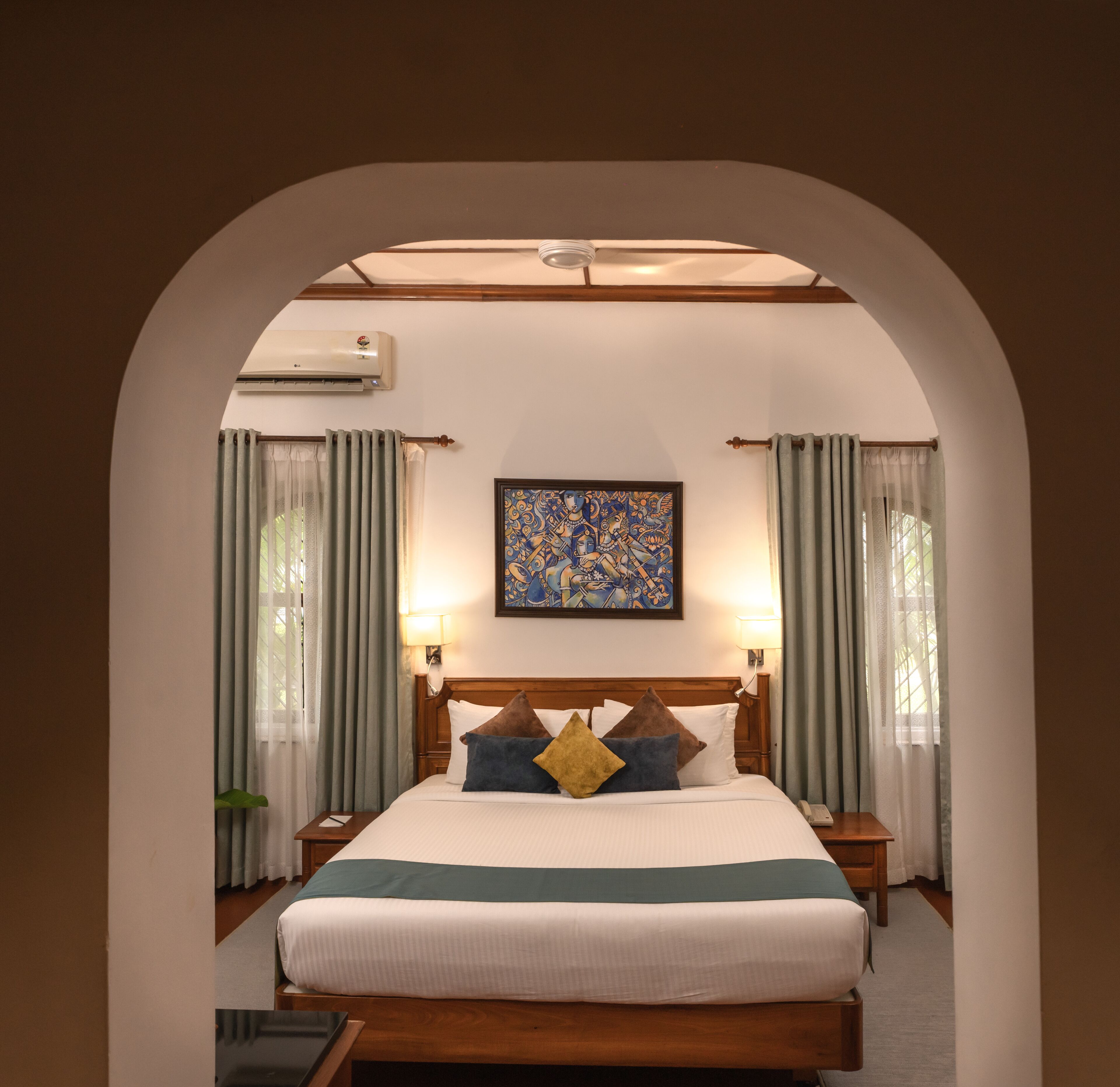 Una habitación de hotel con una cama de madera, un cuadro grande en la pared y un arco de entrada.