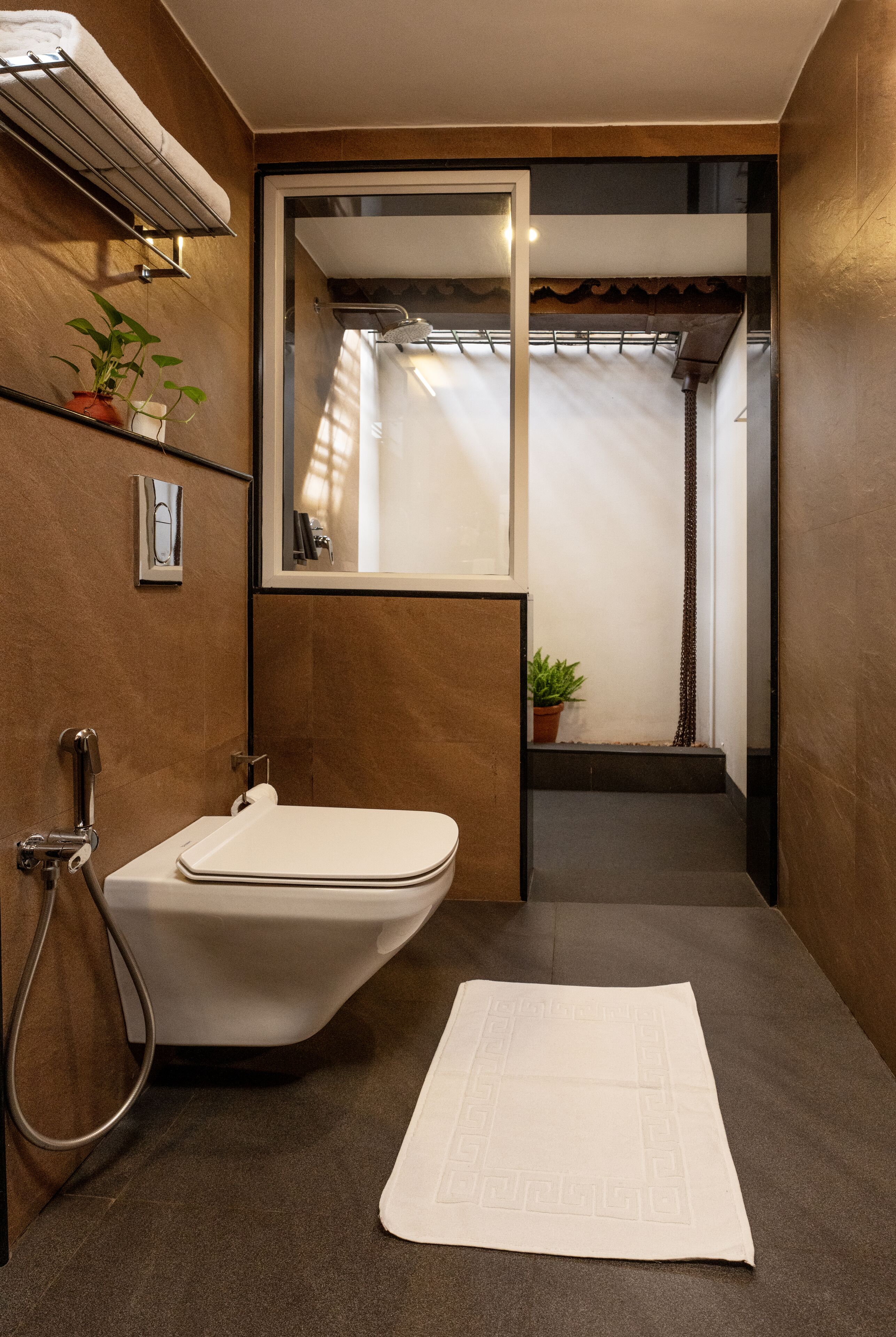 A modern bathroom with a freestanding toilet, a towel rack, and a mirror.