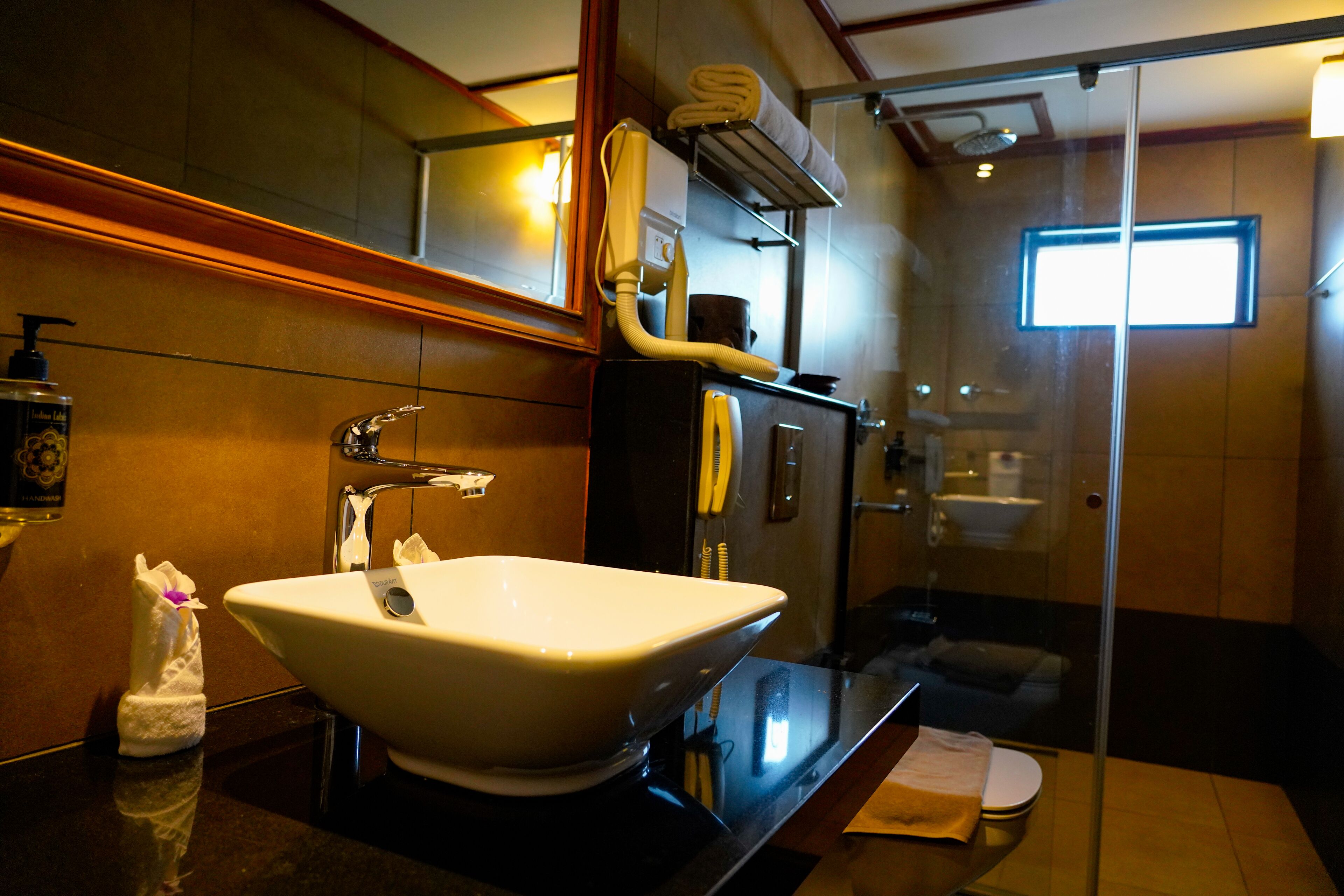 A bathroom with a large white sink, a glass shower enclosure, and a towel rack.