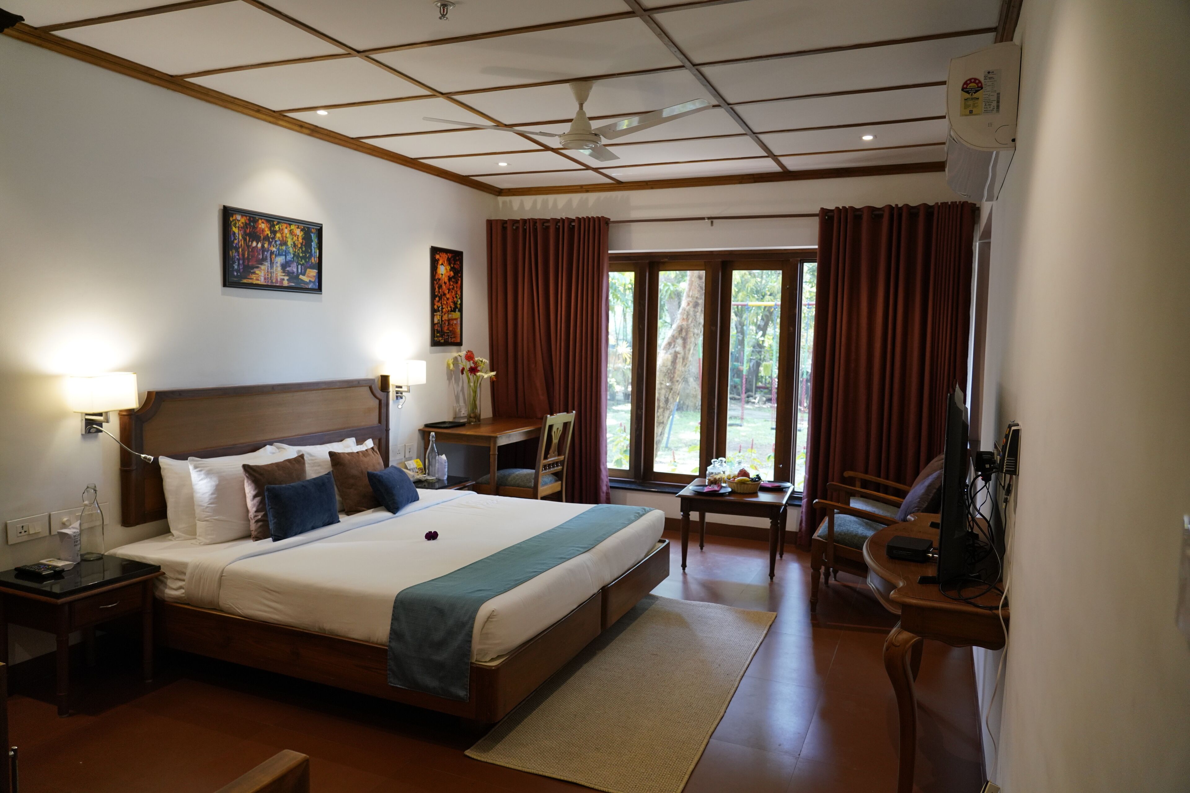 A hotel room with a large bed, a desk, a chair, a TV, and a window with curtains.