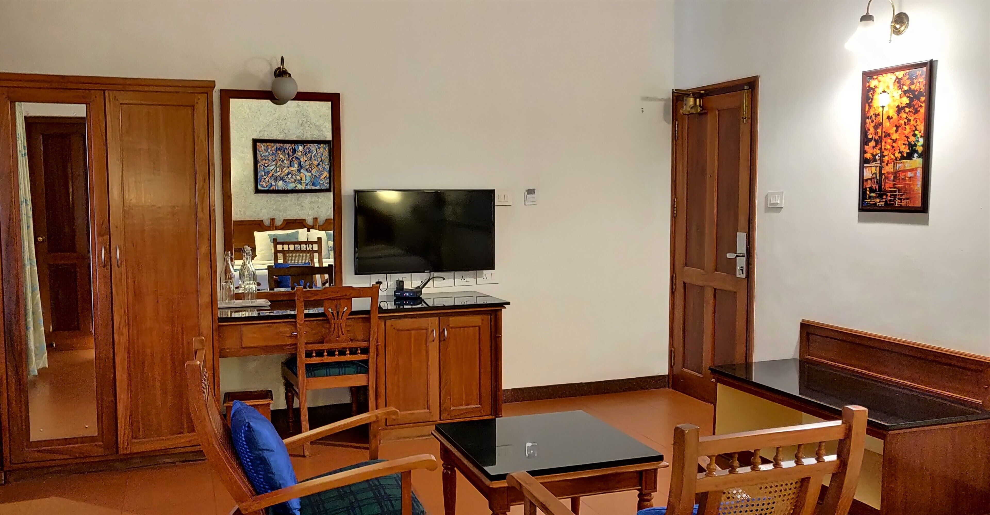 Une pièce comprenant un buffet en bois, un téléviseur, une table à manger avec des chaises et un tableau accroché au mur.