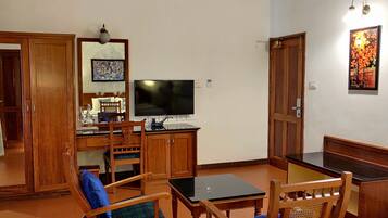 Une pièce comprenant un buffet en bois, un téléviseur, une table à manger avec des chaises et un tableau accroché au mur.