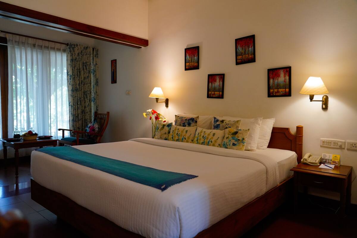 A neatly made bed with a blue accent, a bedside table with a lamp, and a chair.
