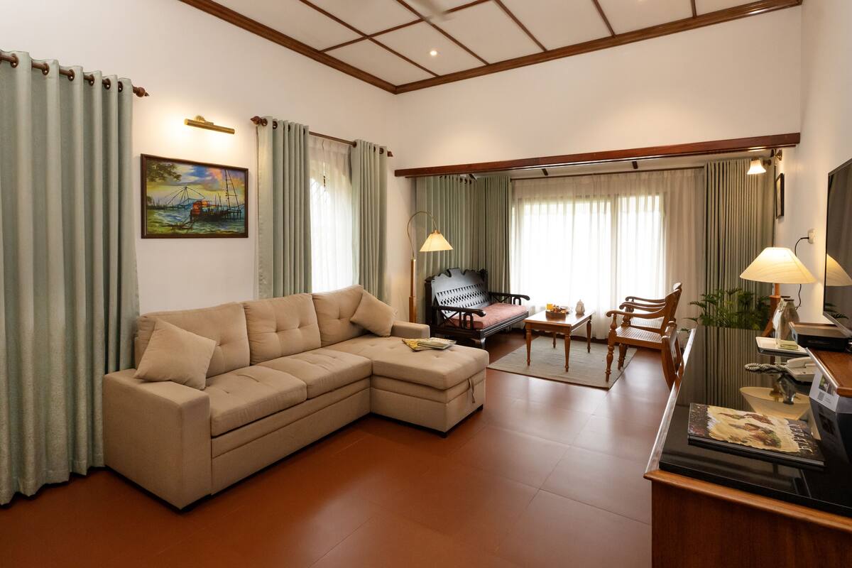 A modern living room with a sofa, a wooden chair, a dining table, and a television.