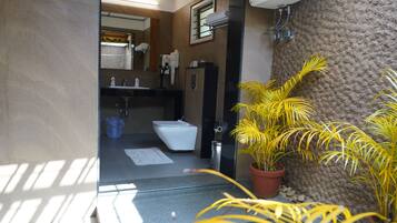 A modern bathroom with a toilet, sink, and mirror. There are potted plants and a towel rack.