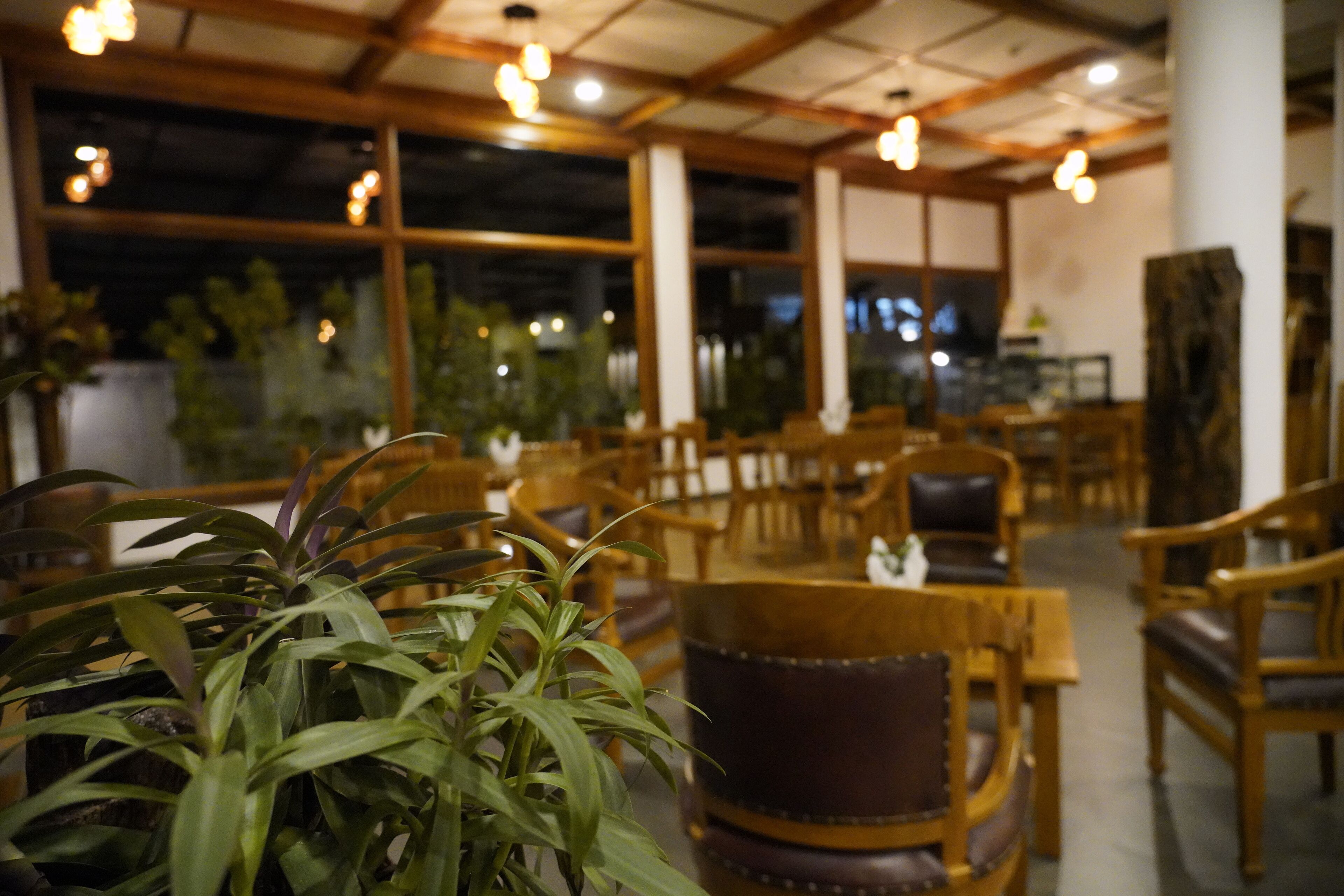 A restaurant interior with wooden furniture, large windows, and hanging lights.