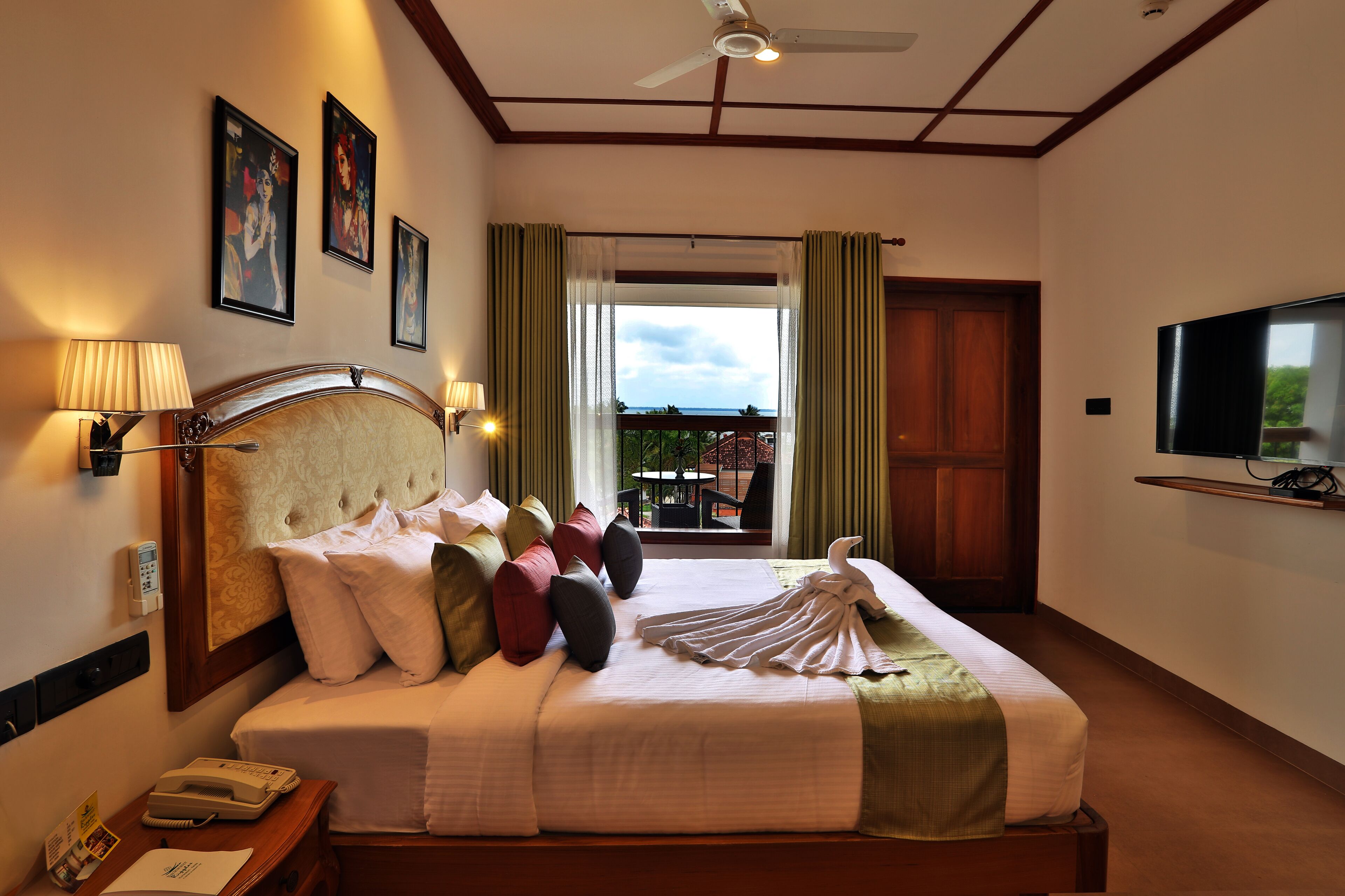Quarto de hotel com cama, televisão, telefone e janela com cortinas.