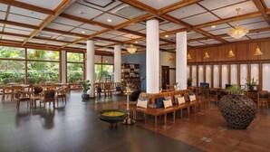 A spacious lobby with wooden furniture, large windows, and a reception desk. - Backwater Ripples Kumarakom (Kottayam)
