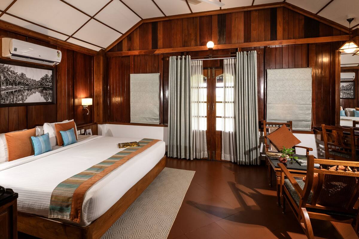 A spacious room with a large bed, wooden furniture, and a dining area.