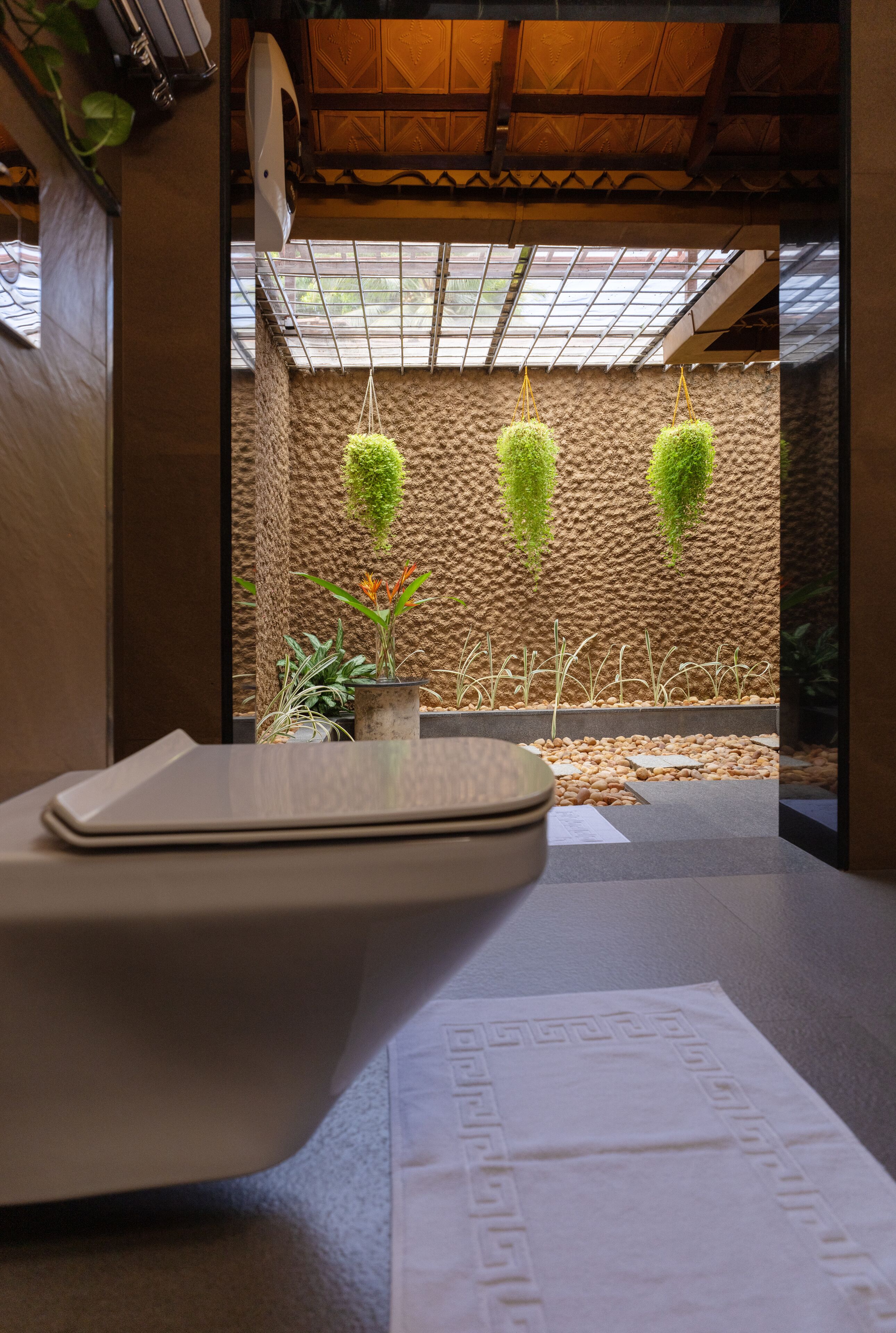 Um banheiro moderno com parede de pedra, plantas penduradas e teto de madeira.