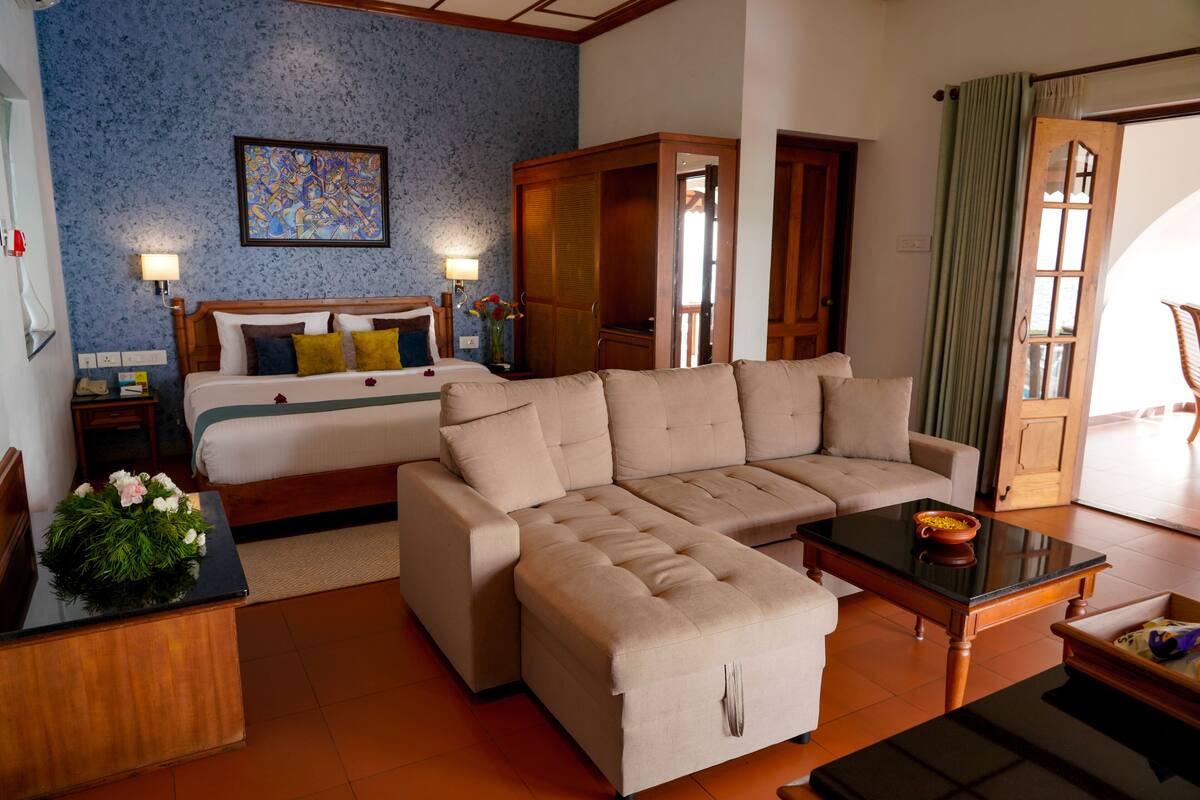 A hotel room with a bed, a sofa, a coffee table, and a wooden wardrobe.