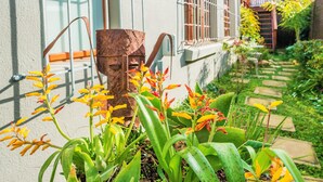 Un jardí amb plantes i un objecte metàl·lic rovellat.