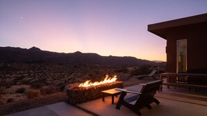 A patio with a fire feature, lounge chairs, and a view of the desert landscape. - Shelter 2 By Homestead Modern (Joshua Tree)