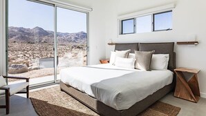 A bedroom with a large bed, a view of a desert landscape, and a window with a view of mountains. - Shelter 2 By Homestead Modern (Joshua Tree)
