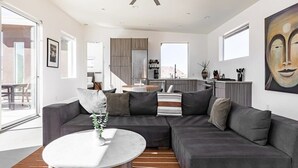 A modern living room with a sectional sofa, a round coffee table, and a ceiling fan. - Shelter 2 By Homestead Modern (Joshua Tree)