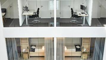 A modern office space with multiple workstations, glass partitions, and a view of the lower level.