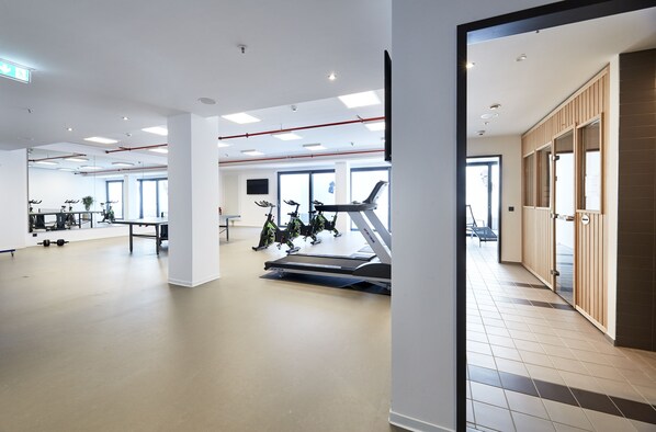 Un gimnasio amplio con cintas de correr, bicicletas estáticas y máquinas de pesas.