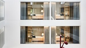 Una habitación de hotel moderna con un separador de vidrio, una cama, un escritorio y un armario.