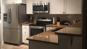 Eine moderne Küche mit Edelstahlgeräten, weißen Schränken und Holzboden.
