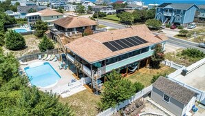 Ein zweistöckiges Haus mit einer großen Terrasse, einem Swimmingpool und Blick aufs Meer.