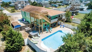 Ein zweistöckiges Haus mit einer großen Terrasse und einem Schwimmbad.