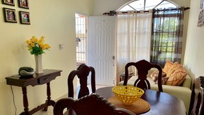 A dining area with a wooden table, chairs, a vase with yellow flowers, and a basket. - Higuey Center City, Candyland 2 bedroom  (Higüey)