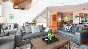 A modern living room with two grey sofas, a wooden coffee table, and a staircase leading to another level. - Alpine townhouse w/ hot tub & A/C (Whistler)