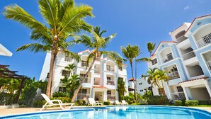Ein Hotel mit Schwimmbad, Palmen und mehreren Balkonen.