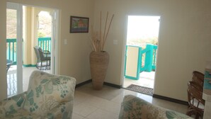 A room with a large woven basket, a sofa with floral upholstery, and a dining area with chairs and a table. - Charming 1BR apt w/ balcony (St John)