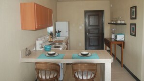 A compact kitchen with a central island, wooden cabinets, a refrigerator, and a microwave. - Charming 1BR apt w/ balcony (St John)