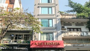 Un hôtel avec une enseigne rouge, de nombreuses fenêtres et un arbre devant.