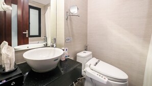 Une salle de bain avec un grand lavabo blanc, un miroir, des toilettes et un porte-serviettes.