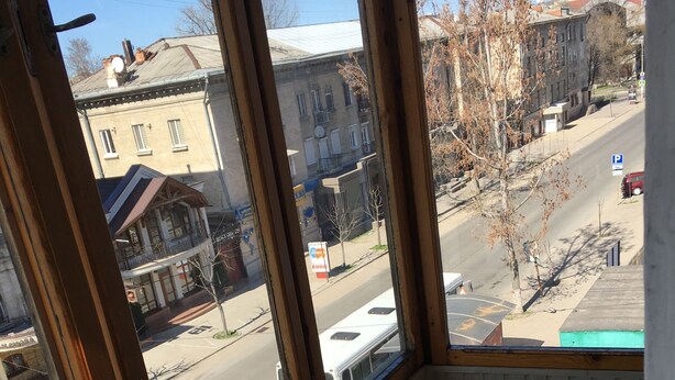 A room with a view of the street, a window with a view of buildings, and a striped rug on the floor. - Nostalgy House Moldova (Râşcani)