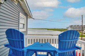 A blue Adirondack chair and a table on a balcony with a view of a body of water and a building in the background. - Waterfront Brigantine Home, Walk to Beach! (Brigantine)