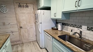 A kitchen with light blue cabinets, a white refrigerator, a dishwasher, a granite countertop, and a stainless steel sink. -  Welcome to SSI...near Pier, Village and Beach! (St Simons)