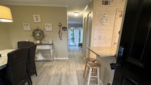A kitchen with a dining area, wooden floors, and a black door. -  Welcome to SSI...near Pier, Village and Beach! (St Simons)