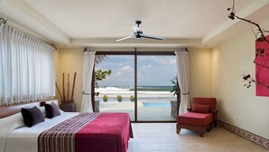 A bedroom with a bed, a chair, and a view of the ocean through a sliding door. - Fort Walker (Beachfront House) (Hacienda Iguana)
