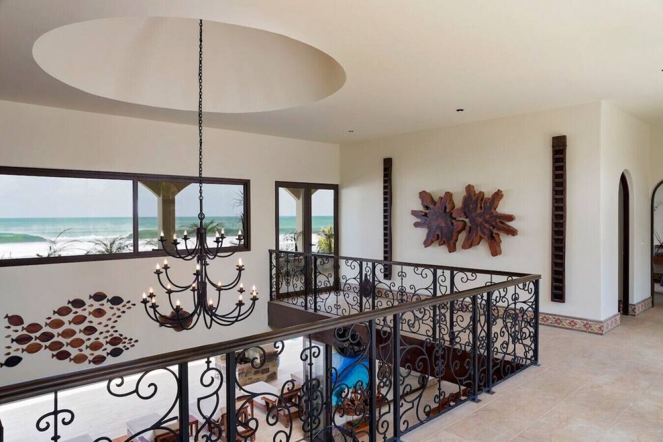 Un intérieur spacieux avec un balcon donnant sur l’océan, un lustre et un élément décoratif mural.